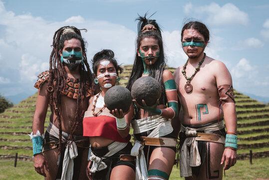 Group of Mayan warriors holding dark earthen ball