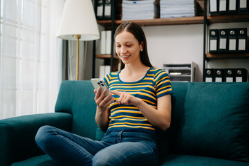 Obraz premium Caucasian woman using the smartphone and tablet on the sofa at home. Embrace Digital Lifestyle