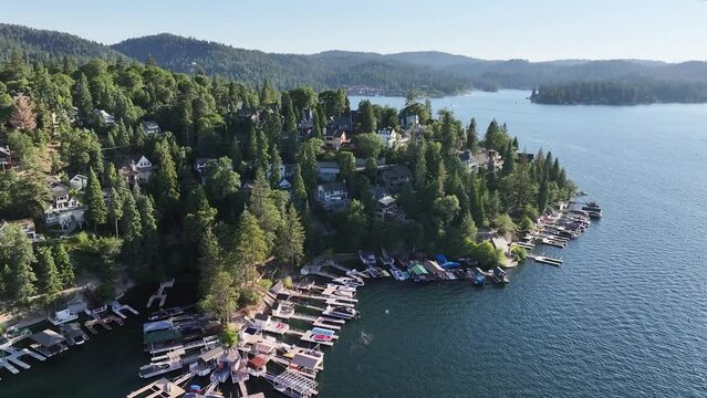 large homes dockside and in the hills of lake arrowhead in california during a sunny day AERIAL DOLLY RAISE UP PAN RIGHT