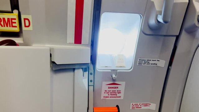 Zoom in on Airbus airplane galley window with door closed and armed during flight. Indoor close up view