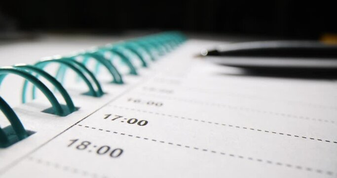 Daily planner with time schedule by clock and ballpoint pen closeup. Working day planning motivation and goals