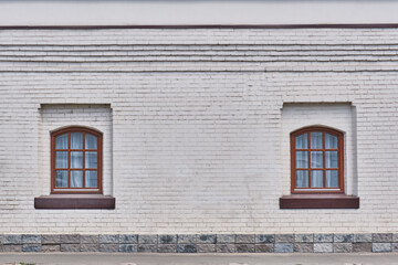Two windows on a white brick wall of a historical building of the 18th century.