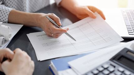 Female accountant pointing with a pen into audit paper while explaining tax counting results, close up. Business audit and finance concepts - 620835675