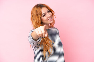 Young caucasian woman isolated on pink background pointing front with happy expression