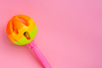 Colorful baby rattle on pink background. Copy space