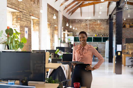 Portrait of happy african american casual businesswoman with tablet in creative office