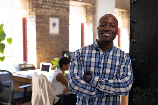 Portrait of happy african american colleagues with arms crossed in creative office