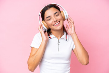 Young caucasian woman isolated on pink background listening music and singing