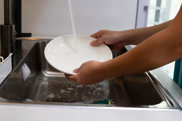 Man washing dish on sink in kitchen room