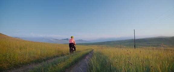 The athlete trains for a long distance. The beautiful landscape with a field in the fog. The woman...