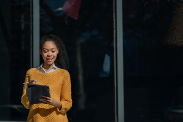 young female using digital tablet outside an office building.