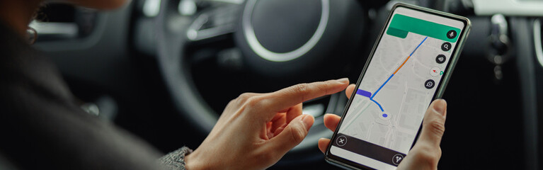 Closeup of female traveler using cell phone with gps navigation app on screen while sitting in car