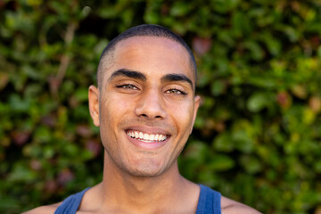 Portrait of happy biracial man with buzz cut hair smiling in sunny garden