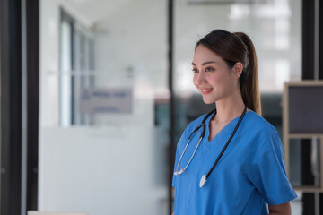 Portrait young and attractive confident Asian female doctor wearing a blue gown. Successful doctor career concept