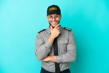 Young security man isolated on blue background with glasses and smiling