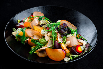 Salad with bacon, persimmon, arugula, olives, blue cheese, cashews and lettuce in a plate.