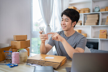 Fototapeta na wymiar Online shopping business owner is talking on the phone with a customer to jot down the delivery address and delivery schedule, SME entrepreneur online shopping, Packaging box Sell online.