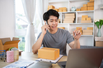 Online shopping business owner is talking on the phone with a customer to jot down the delivery address and delivery schedule, SME entrepreneur online shopping, Packaging box Sell online.