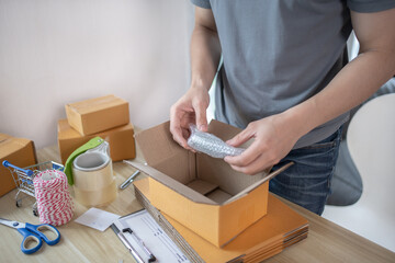 Fototapeta na wymiar Efficient Home-Based Delivery, Man Packing Items into Post Box for Customer Shipping, Online Shopping and Small Business Entrepreneurship, Packing box, Sell online, Freelance working.