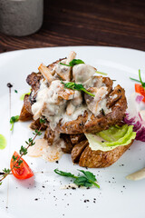 Beef steak with rustic potato wedges, mushrooms, sauce, tomatoes, lettuce and herbs, closeup.