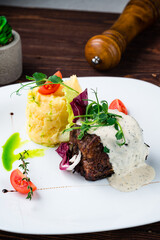 Beef steak with mashed potatoes, tomatoes, lettuce, herbs and sauce, restaurant menu.