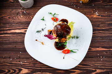 Beef steak with mashed potatoes, cherry tomatoes, greens and sauce in a plate, fresh meal.