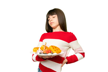 Little girl holding waffles over isolated chroma key background suffering from backache for having made an effort