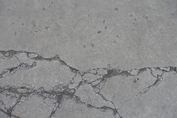 Worn dry light grey concrete slab with numerous cracks