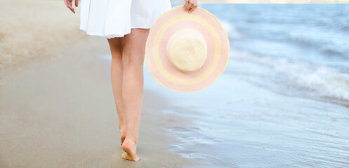 Young woman on a beach holding a white hat. Legs close up - 620855200
