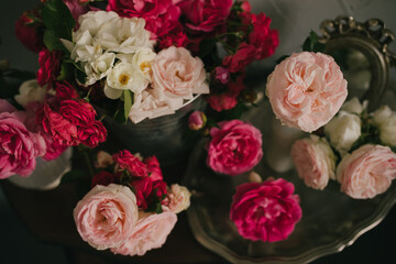 Still life with many different garden roses on a vintage table on grey background.