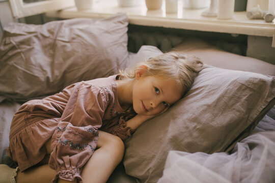 Cute little girl resting on a bed with natural cotton linen.