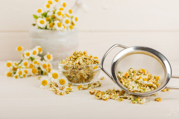 Dried chamomile tea in infuser on texture table.dry chamomile. Chamomile tea. flat lay. Composition with a bouquet and chamomile inflorescences in a mortar. Herbal drink. Soothing and tonic tea. copy 