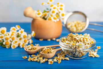 Dried chamomile tea in a bowl on a texture table.dry chamomile. Chamomile tea. flat lay. Composition with a bouquet and chamomile inflorescences in a mortar. Herbal drink. Soothing and tonic tea. 