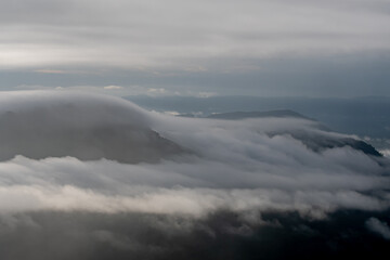 Fototapeta na wymiar White clouds between mountain ranges, free space and fresh mountain air.