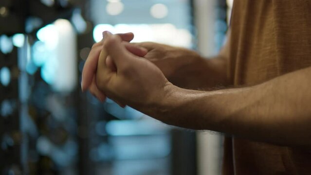 Close-up - Man stretching wrist in gym, hands warm up routine before workout.
