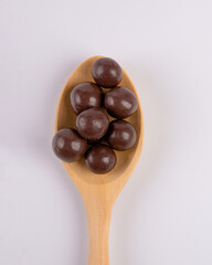 Chocolate balls on wooden spoon on white background.