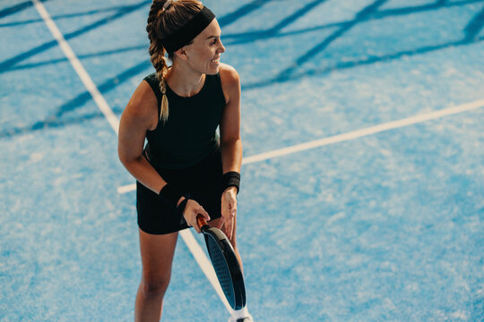 Sportswoman standing on the padel court with her racket, ready for match point