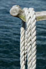 Wood rod with mooring rope hanging over the water in the summer.