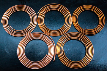 Twisted new copper tubes on a black background.