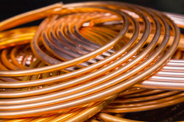 Twisted new copper tubes on a black background.