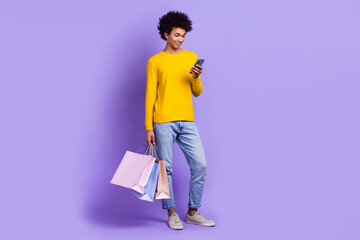 Full length body view cadre of young guy student shopping black friday read more propositions phone isolated on purple color background