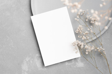 Wedding invitation card mockup with dry gypsophila flowers decor on grey background, top view with...