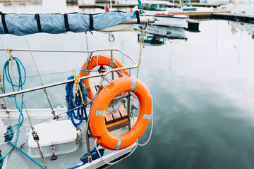 Bright orange lifebuoy on a white yacht side. Blue sea background. Safety, safe traveling