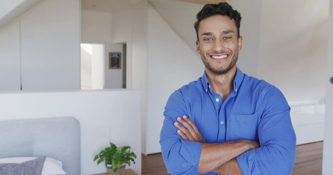 Portrait of happy biracial man smiling in modern apartment, copy space, slow motion