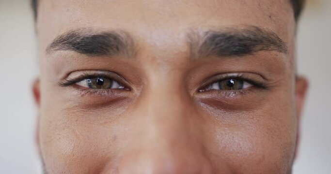 Portrait close up of green eyes of happy biracial man smiling, copy space, in slow motion
