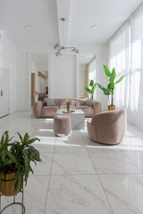 living room with soft beige furniture in a light luxury interior design of a modern apartment in a minimalist style with marble trim and huge windows. daylight inside.
