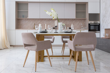 stylish kitchen and a set dining table in a light luxury interior design of a modern apartment in a minimalist style with marble trim and huge windows. daylight inside.