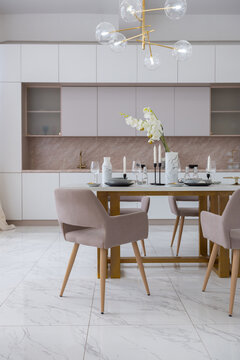 stylish kitchen and a set dining table in a light luxury interior design of a modern apartment in a minimalist style with marble trim and huge windows. daylight inside.
