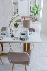 stylish kitchen and a set dining table in a light luxury interior design of a modern apartment in a minimalist style with marble trim and huge windows. daylight inside.