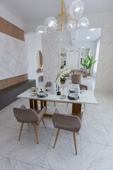 stylish kitchen and a set dining table in a light luxury interior design of a modern apartment in a minimalist style with marble trim and huge windows. daylight inside.